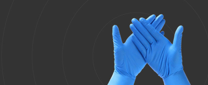 Dark gray background with pair of royal blue nitrile gloves on hands